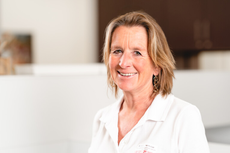 Dr. med. Kathrina Huber, Fachärztin bei RADIO-LOG, lächelt freundlich in die Kamera; sie trägt eine weiße Bluse und goldene Ohrringe. Das Bild spiegelt die patientenorientierte und wohnortnahe medizinische Versorgung durch das interdisziplinäre Team von RADIO-LOG wider, das Radiologie, Strahlentherapie, Allgemeinmedizin, Gynäkologie und Pädiatrie an mehreren Standorten in Bayern anbietet.