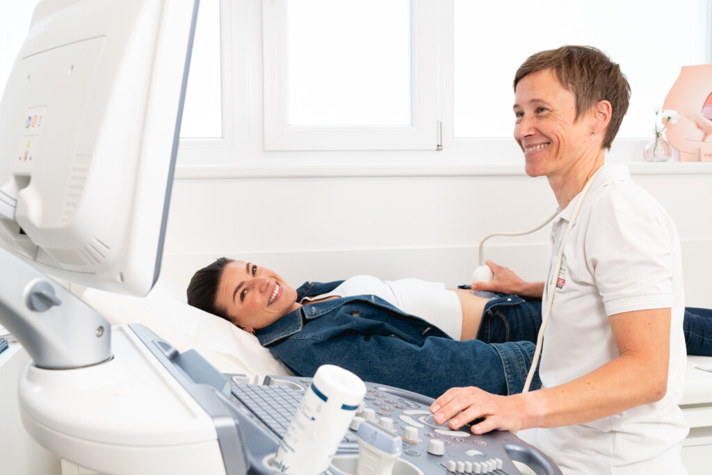 Eine Ärztin führt in einem hellen Behandlungsraum eine Ultraschalluntersuchung bei einer Patientin mit urogynäkologischen Beschwerden durch; beide wirken entspannt. Das Bild steht für die patientenzentrierte, fachübergreifende Diagnostik und Betreuung bei RADIO-LOG an mehreren Standorten in Bayern.