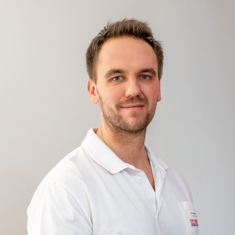 MUDr. Petr Vosátka, ein Arzt mit kurzen braunen Haaren und hellem Bart, steht vor einem hellen Hintergrund in einem weißen Hemd und blickt in die Kamera. Das Porträt ist auf der Website von RADIO-LOG zu sehen, einem Gesundheitsdienstleister in Bayern, der patientenzentrierte radiologische und medizinische Versorgung an mehreren Standorten anbietet.